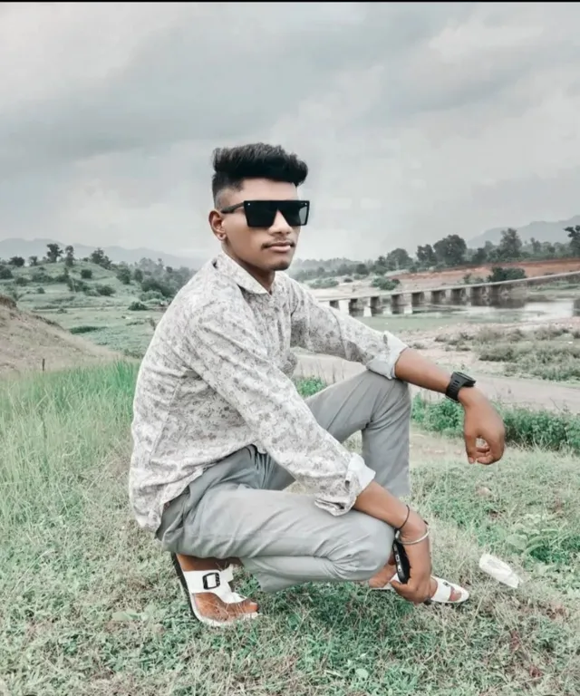 a man sitting on the ground wearing sunglasses