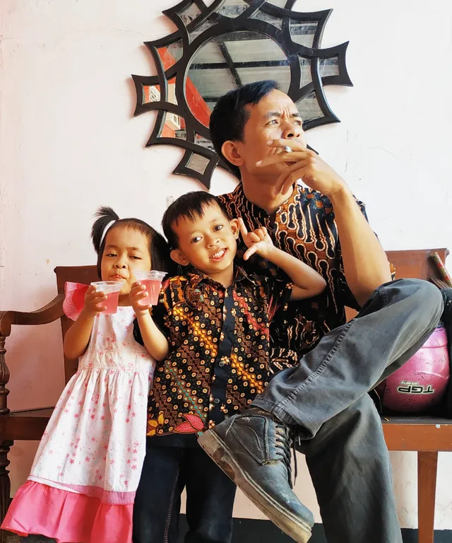 a man sitting on a bench with two children