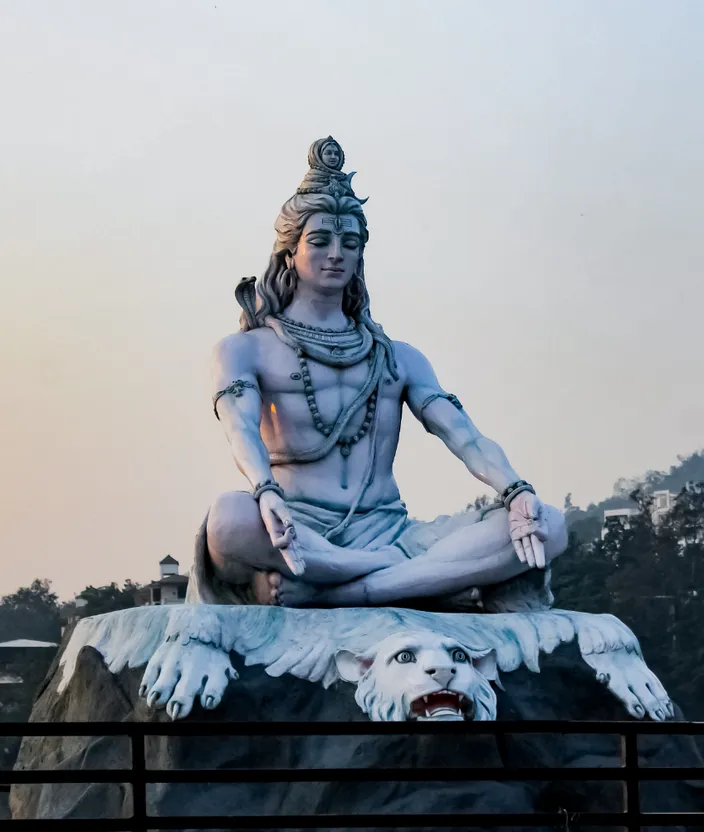 a statue of a man sitting on top of a white dog. sky, sculpture, statue, art, monument, leisure, kneeling, chest, temple, sitting