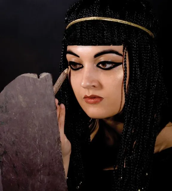 a woman with long black hair holding a rock doing eye make up