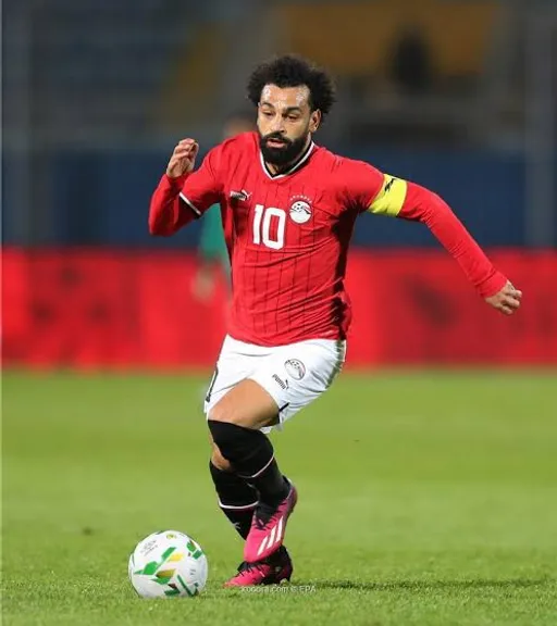 a man in a red jersey kicking a soccer ball