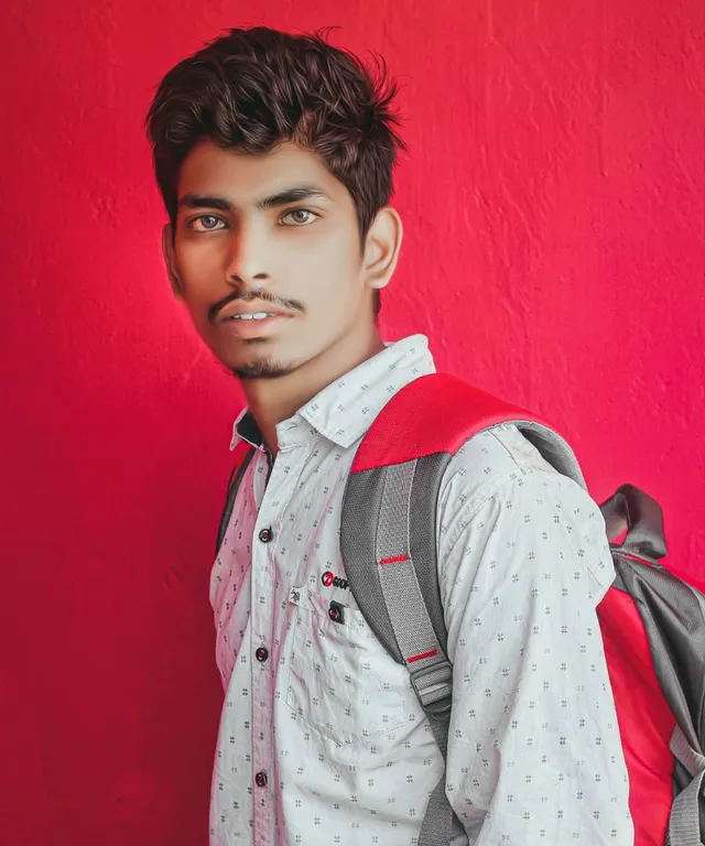 a man with a backpack standing in front of a red wall