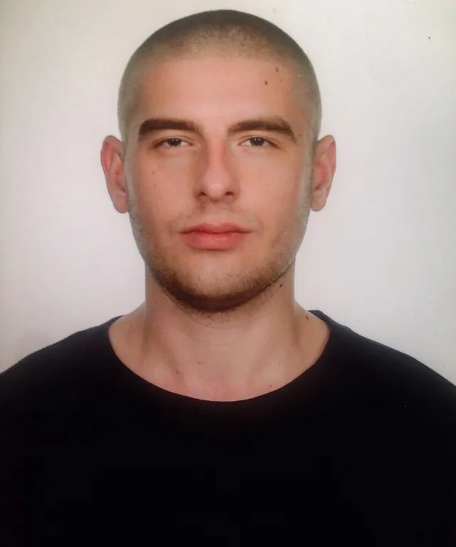 a man with a shaved head and black shirt