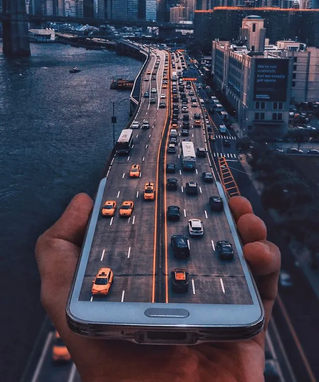 a person holding a cell phone with a city in the background