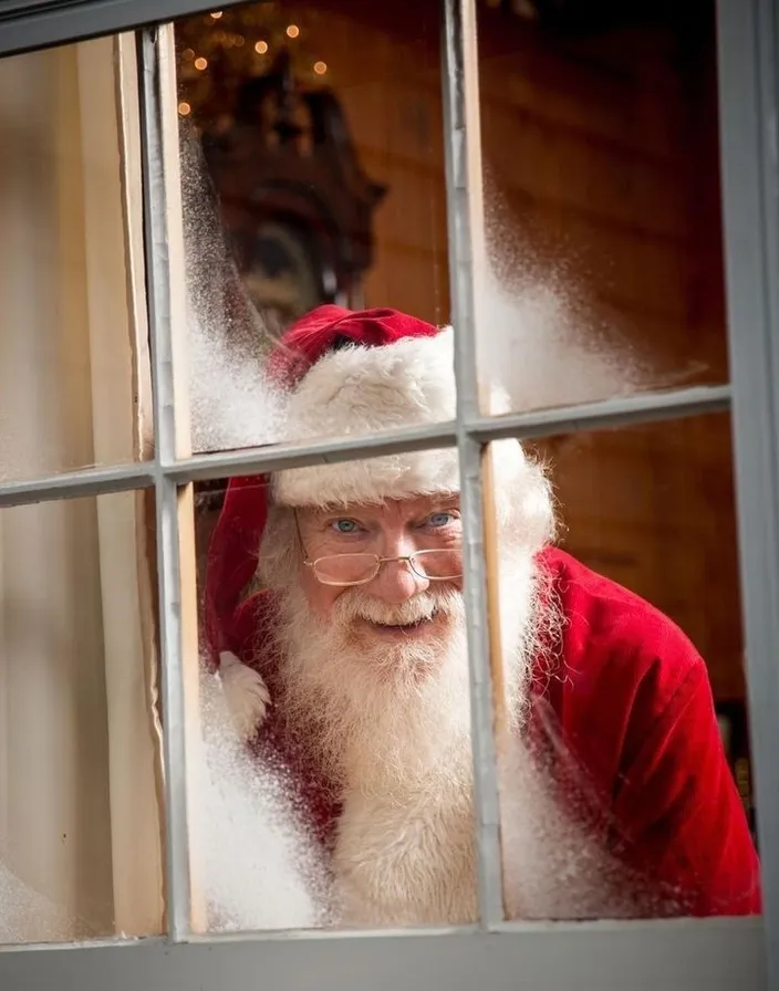 a man dressed as santa claus looking out of a window