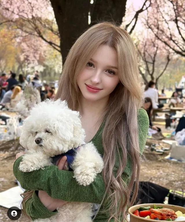 a woman holding a white dog in a park