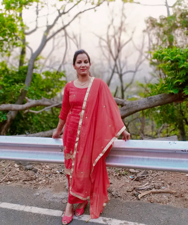 a woman in a red dress standing on a road