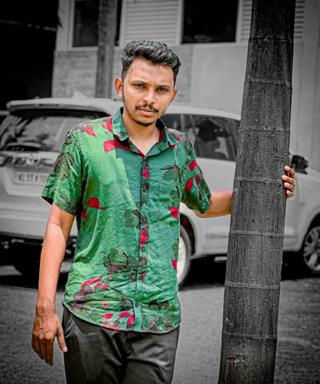 a man standing next to a tree on a street