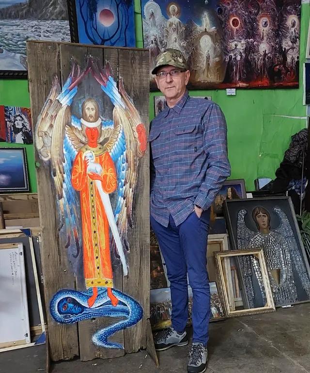 a man standing next to a painting of an angel