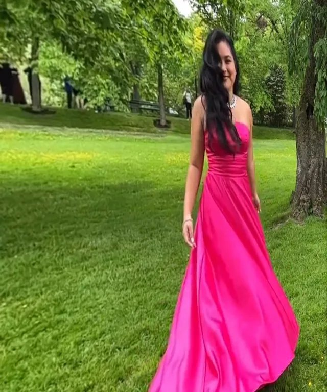 a woman in a pink dress standing in the grass