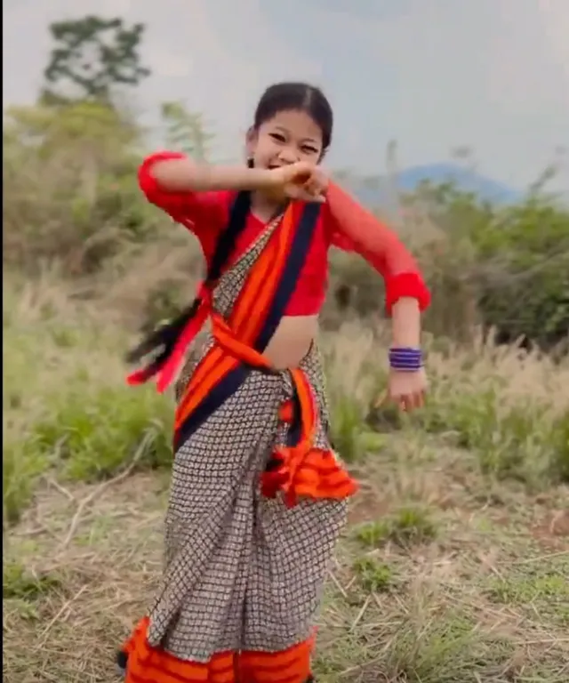 a woman in an orange and blue sari poses for a picture