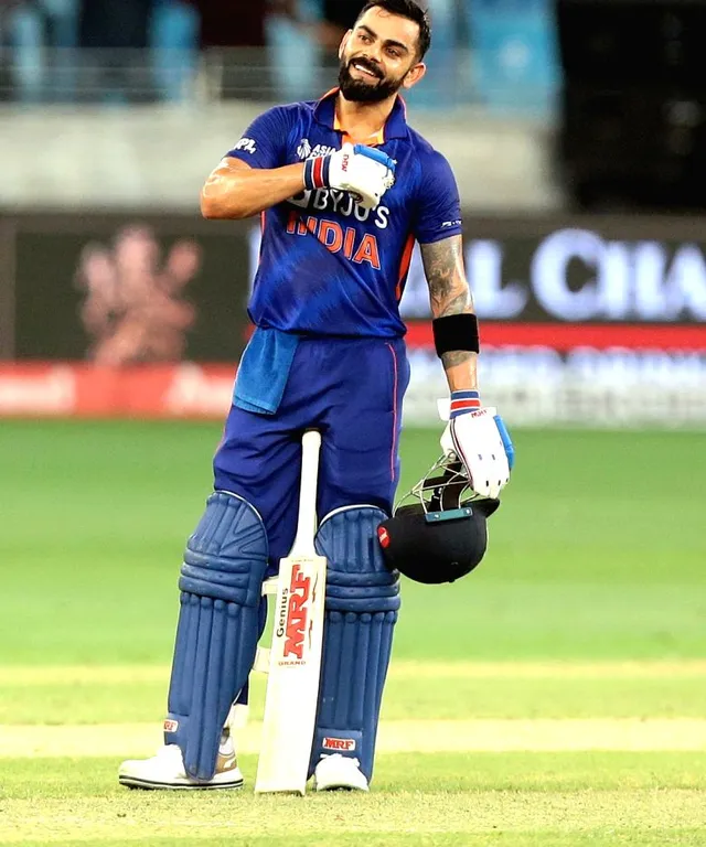 Virat Kohli standing on top of a field holding a bat make him look like real Virat Kohli and he has done century