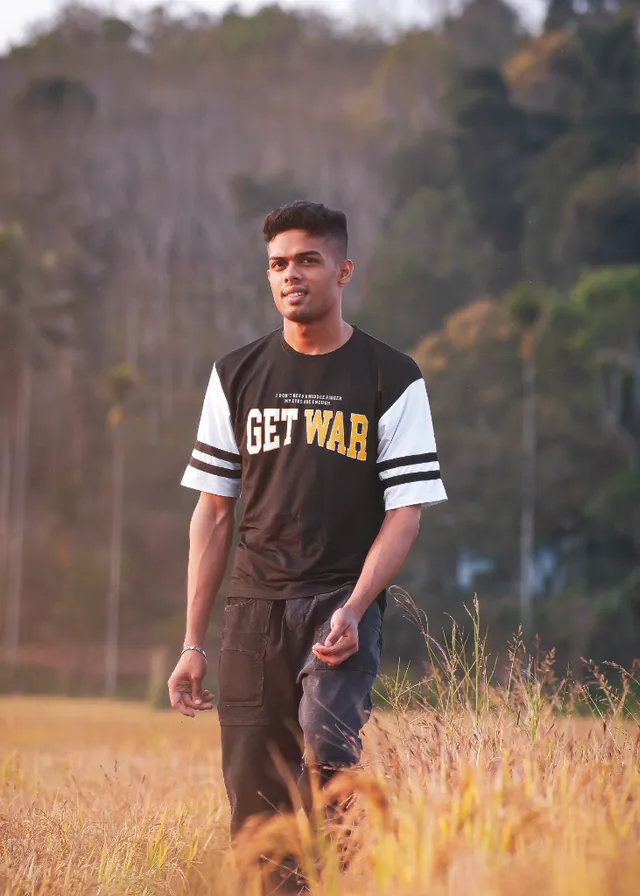 a man standing in a field of tall grass. sleeve, flash photography, grass, happy, grassland, people in nature, t-shirt, landscape, player, prairie