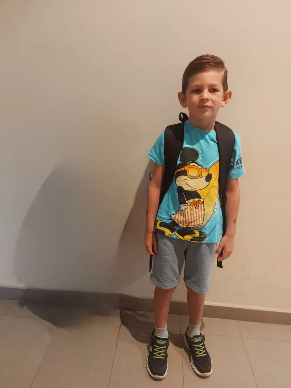 a young boy standing in front of a wall