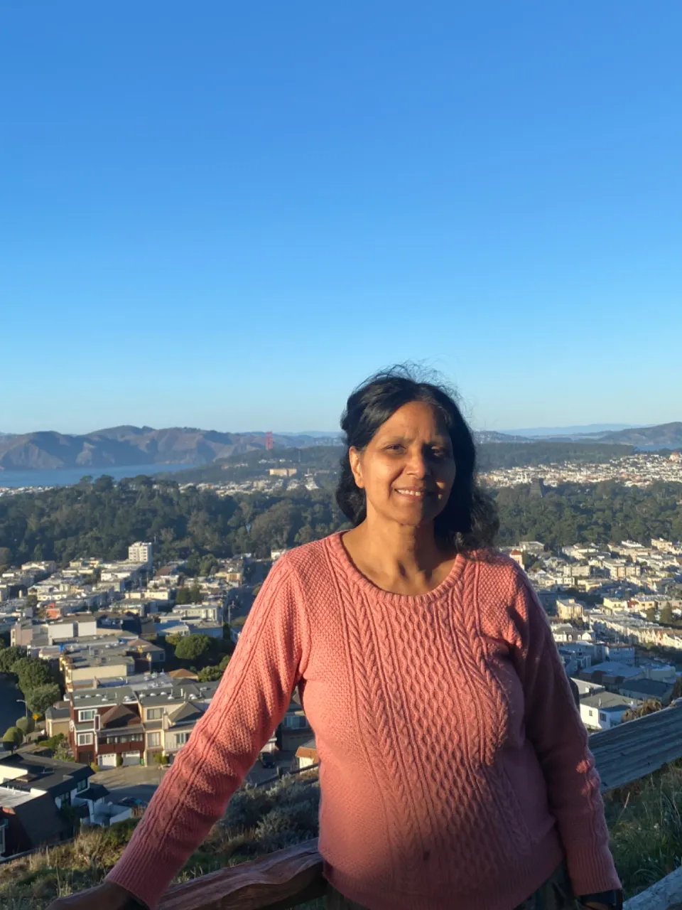 a woman standing on top of a hill next to a city