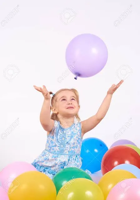 a little girl sitting on top of a pile of balloons