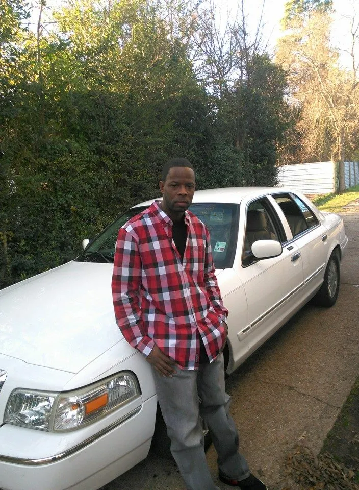 a man in louis vuitton standing next to a white car