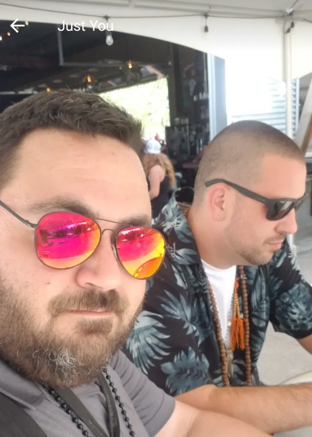 two men wearing sunglasses sitting next to each other. glasses, vision care, hairstyle, eyewear, beard, sunglasses, goggles, cool, facial hair, fun