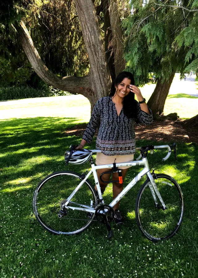 a woman standing next to a bike in the grass