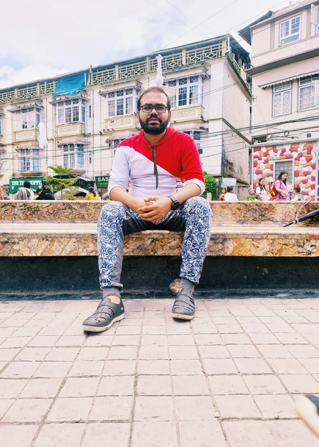 a man sitting on a bench in front of some buildings