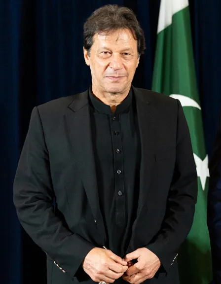 a man in a suit standing in front of a flag