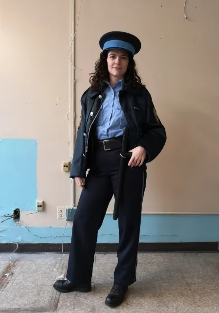 a woman in a police uniform standing in a room turn the police uniform into a prison uniform