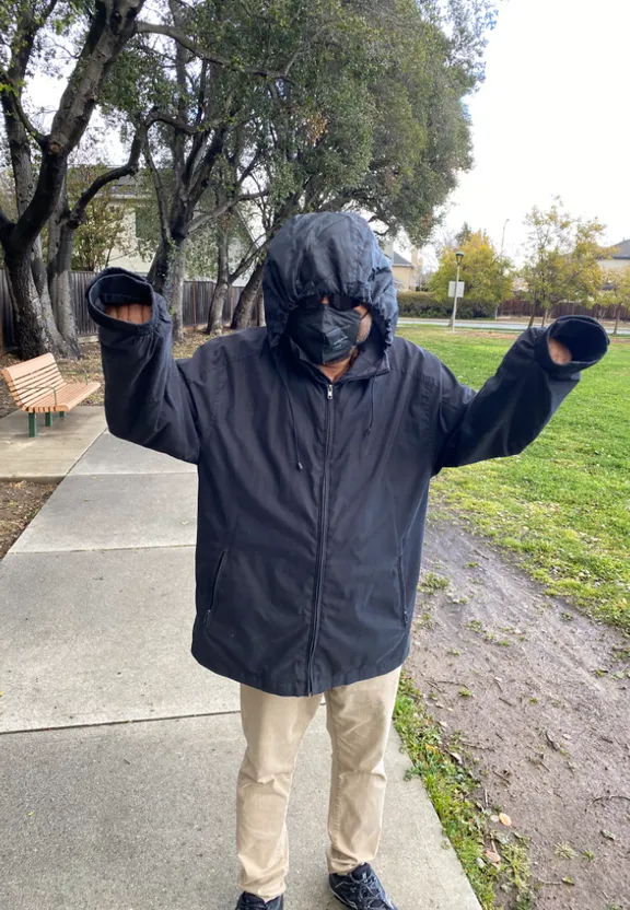 a man wearing a black jacket and covering his face