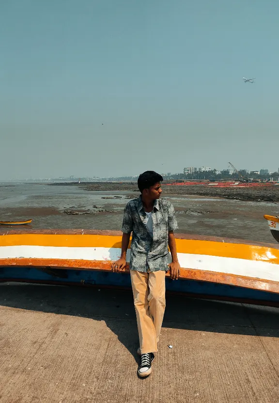 a man standing next to a boat on the beach