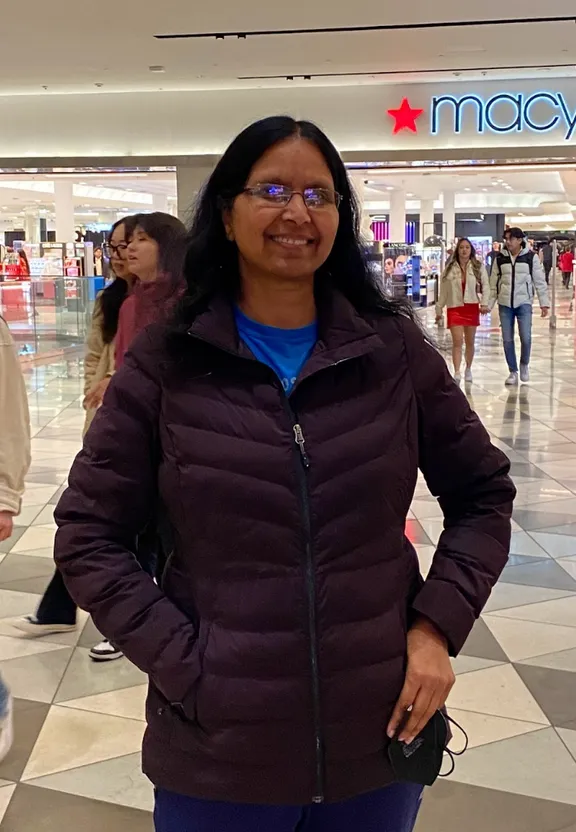 a woman in a jacket standing in a mall