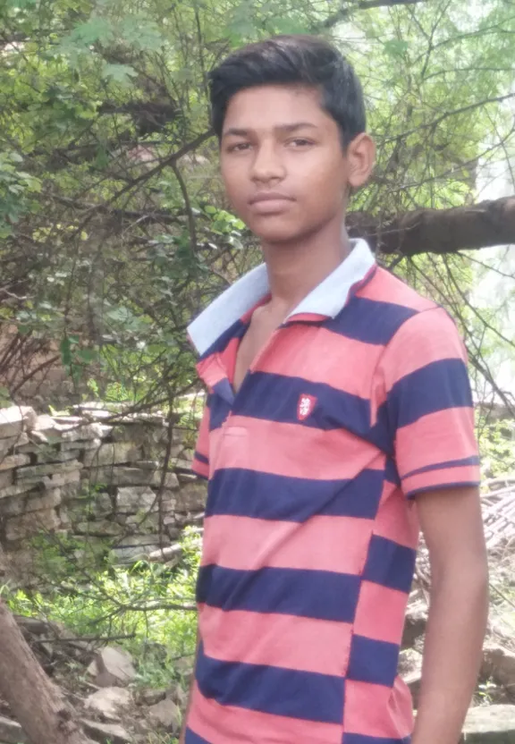 a young man in a striped shirt standing in a wooded area