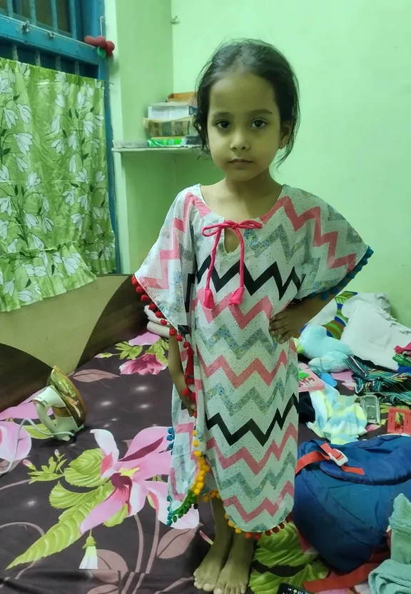 a little girl standing on a bed in a room