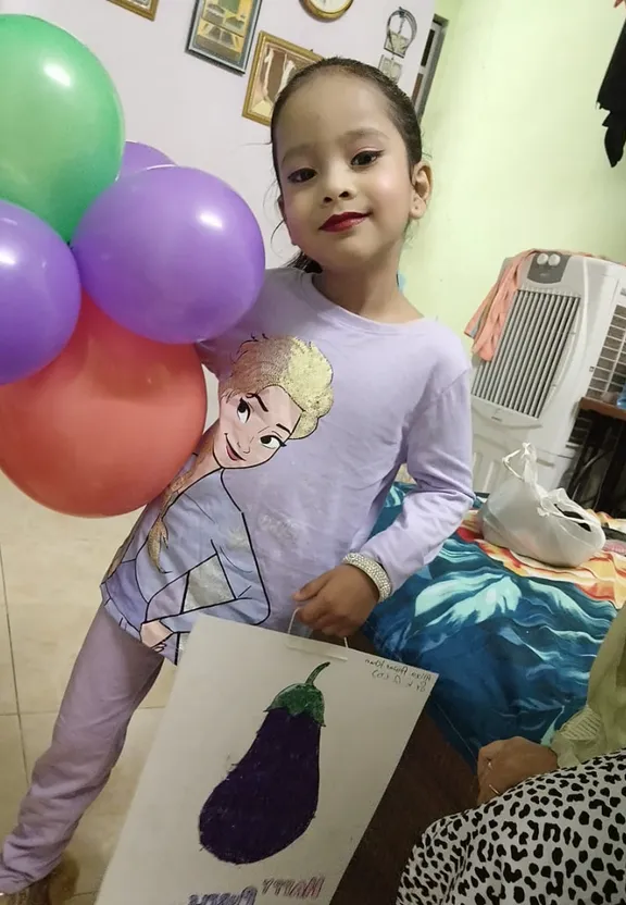 a little girl holding a picture of herself with balloons