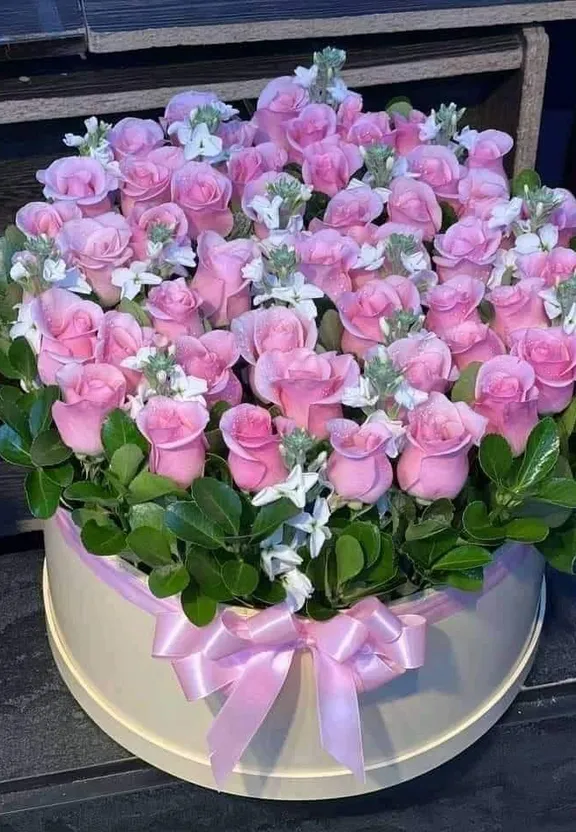 a bouquet of pink roses in a white box