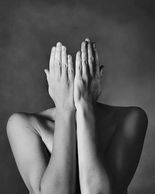 a naked woman covering her face with her hands