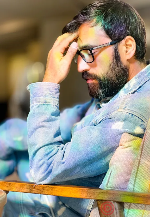 a man sitting in a chair with his hand on his head