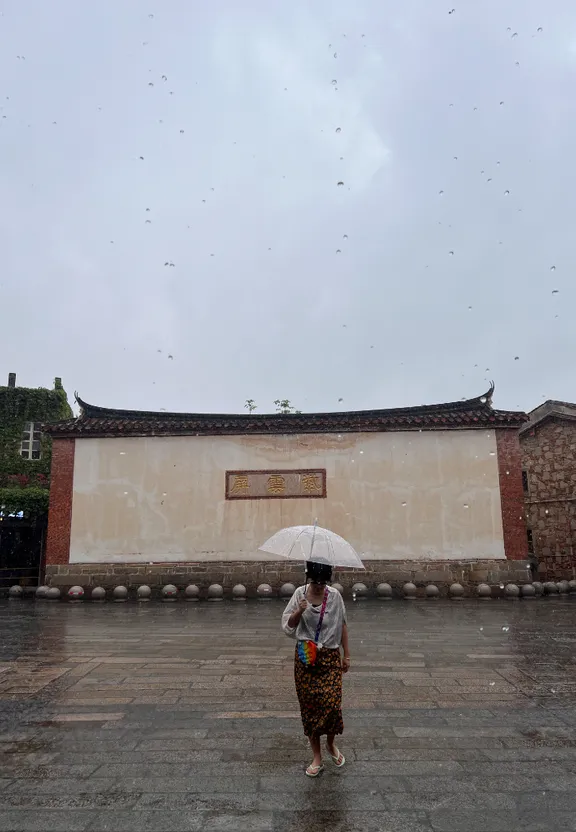 a woman standing in the rain with an umbrella