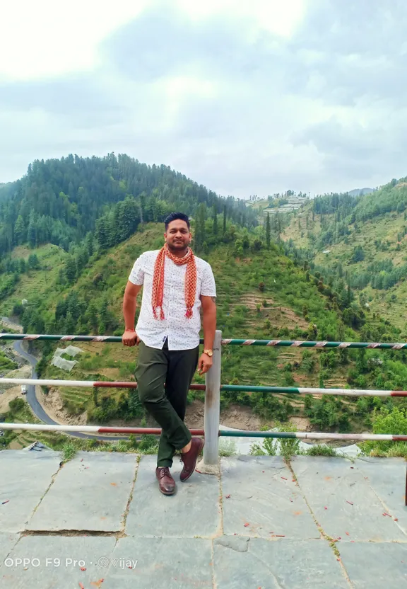 a man standing on top of a hill next to a lush green hillside