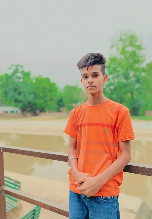 a young boy standing next to a wooden fence