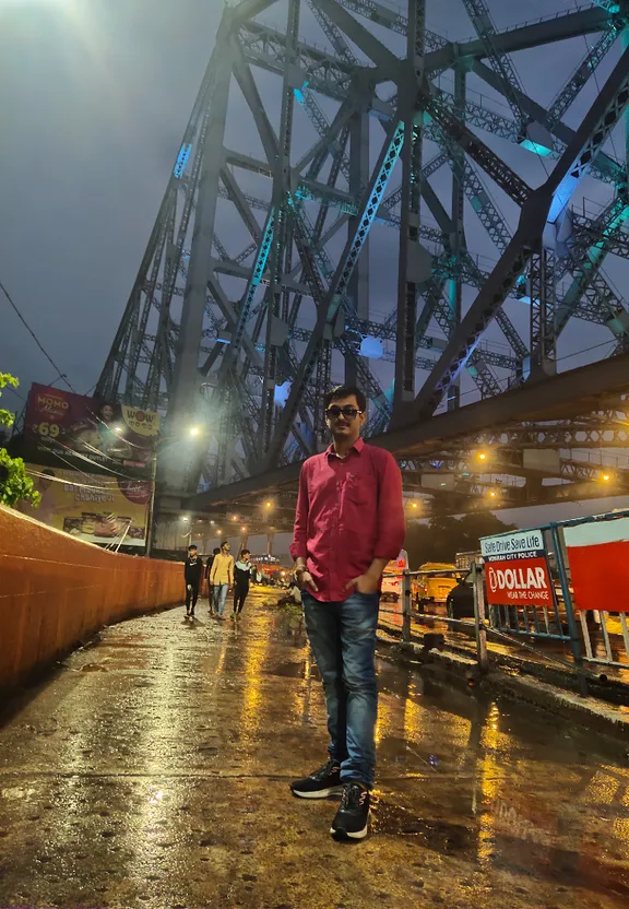 a man standing in the rain under a bridge