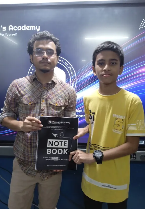 two young men standing next to each other holding a note book