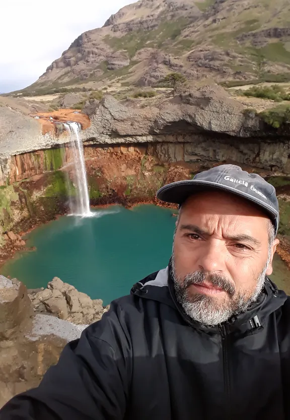 a man taking a selfie in front of a waterfall