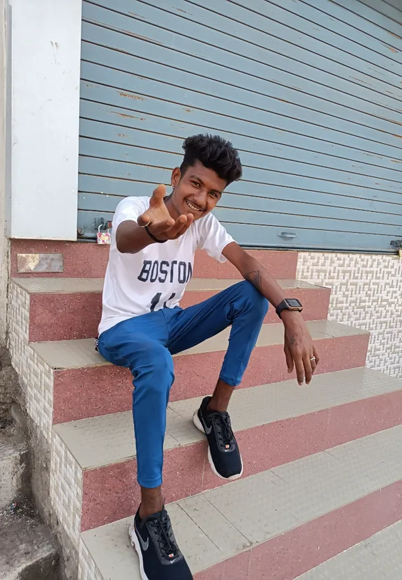 a young man sitting on a set of stairs giving a thumbs up