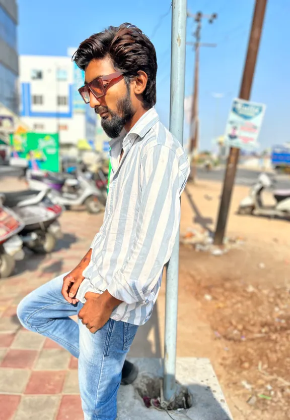 a man with glasses leaning against a pole