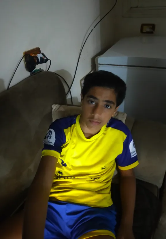 a young man in a yellow and blue shirt sitting on a couch