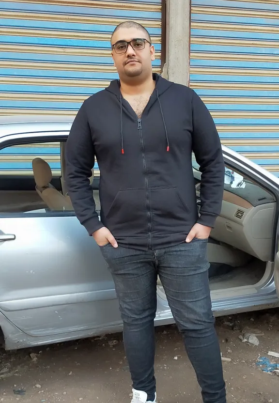 a man standing in front of a car with his hands in his pockets