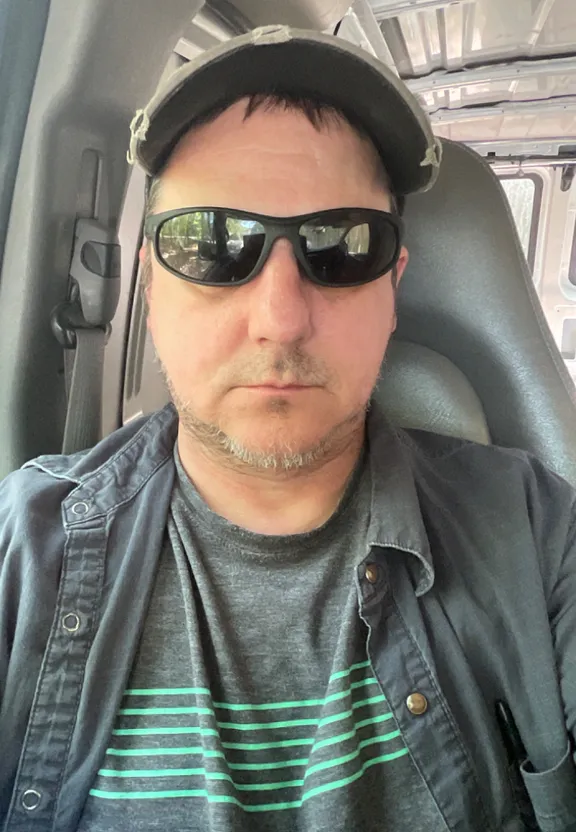 a man wearing sunglasses and a hat in a vehicle