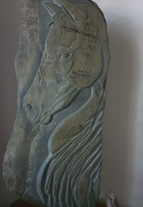 a stone sculpture of a horse with a long mane