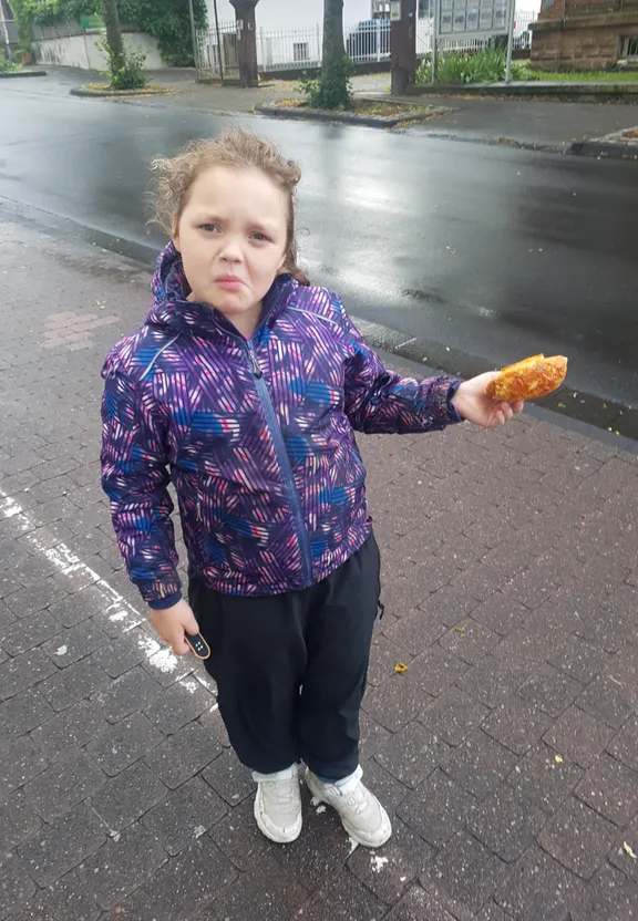 a little girl holding a piece of food in her hand