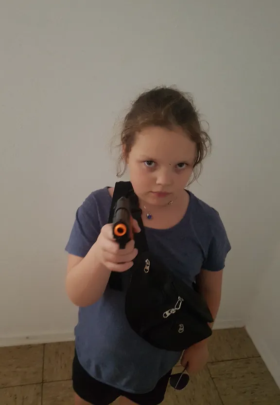 a little girl holding a toy gun in her hand