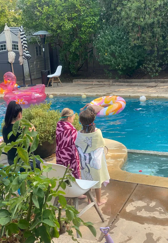 a group of people sitting next to a swimming pool